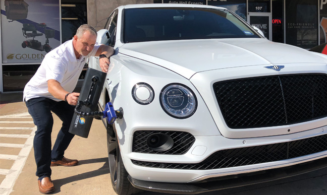 dent HQ mechanics checking hail damage of a white car